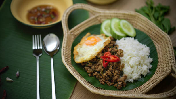 istock Stir fried minced pork with basil (Pad ka prao), rice fried egg serving on wicker plate and silverware 1249733583