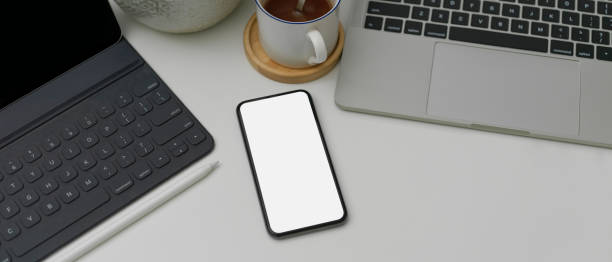istock Blank screen smartphone on white office desk with laptop, digital tablet and coffee cup 1249734911