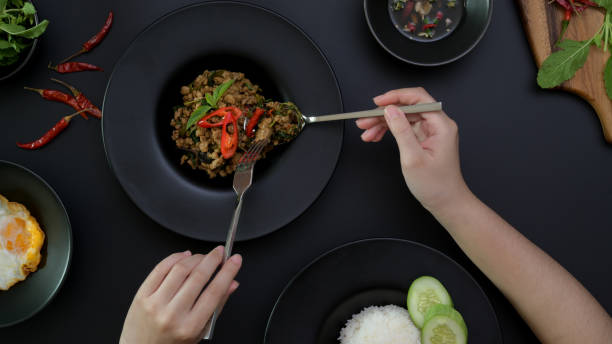 istock Female eating Stir fried minced pork with basil (Pad ka prao), fried egg and chili fish sauce on black dinning table 1249734938