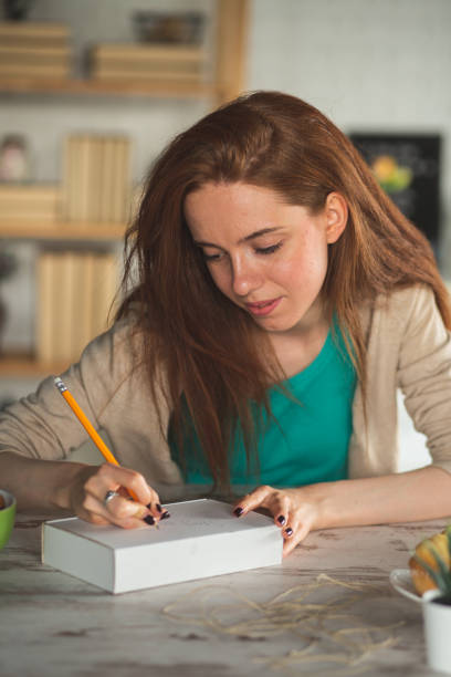 istock Young woman writing on a care package 1249735605