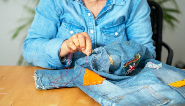istock an elderly woman hands sewing on fabric jeans, 1249736023