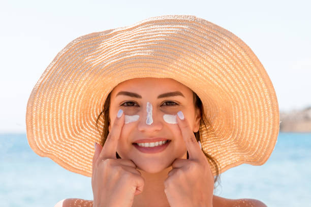 istock Smiling woman in hat is applying sunscreen on her face. Indian style 1249740638