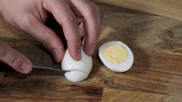 istock Man hands Cutting Boiled Egg on Wooden Board With Knife. 1249743906