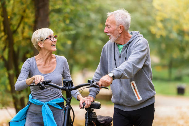 istock Cheerful active senior couple with bicycles walking through park together 1249744050