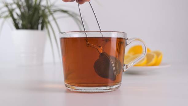 istock Making tea in glass cup with tea strainer on white kitchen table. Close up. 1249744268