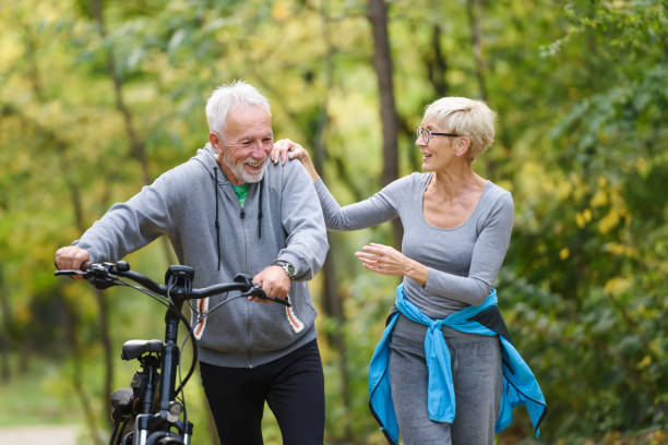 istock Cheerful active senior couple with bicycles walking through park together 1249745470