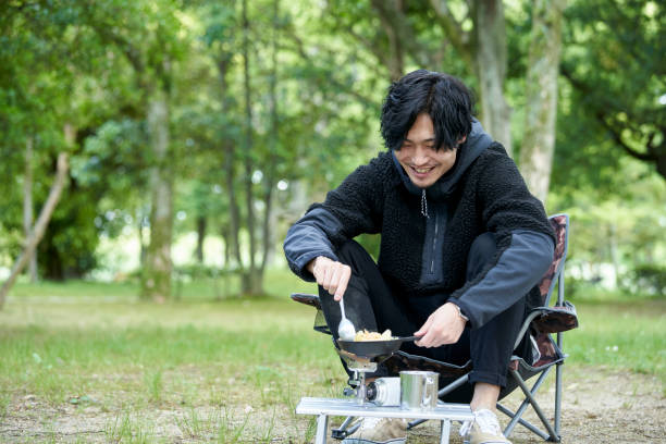 A young Japanese man cooking alone in a camp