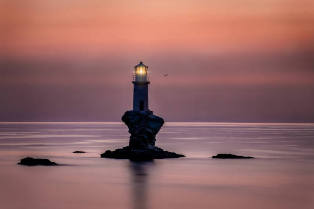 istock A lighthouse on a rock in calm sea during sunrise 1249750142