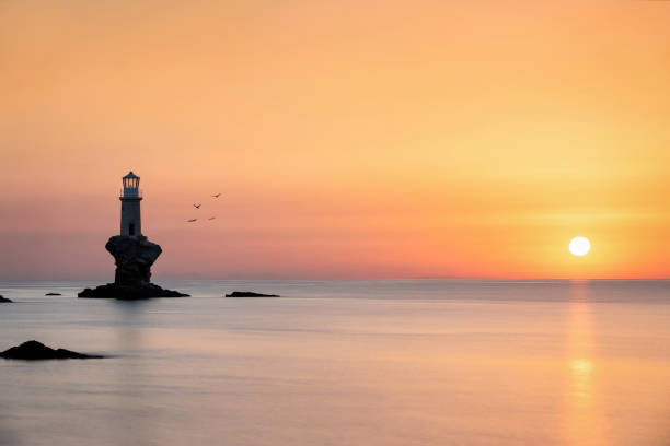 istock Silhouette of a lighthouse on a rock during sunrise 1249750846