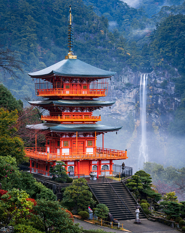 Nachi, Japan - November 19, 2018 : Sanjudo Pagoda, a red three-story pagoda of Seigantoji Temple, with the Nachi Falls in the background, The temple was built in 4th century.