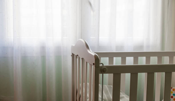 Covid quarantine and motherhood a baby white craddle corner with dim relaxing light from a window with curtains. Concept of motherhood and having a baby at home with copy space. crib stock pictures, royalty-free photos & images