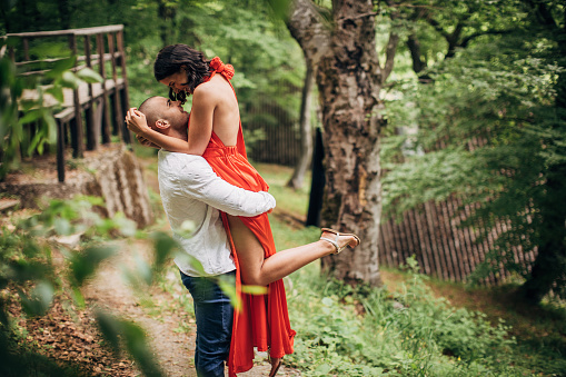 Romantic moment. Beautiful young elegant couple. Young man holding up his girlfriend in nature.