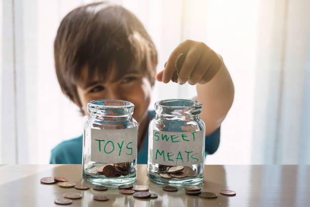 istock Smiling boy keeps coins in two jars for sweets and toy 1249754093