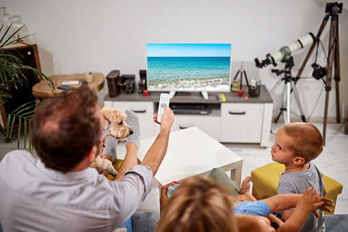Family in isolation / quarantine looking at the sea beach on a TV. No travel this year?
