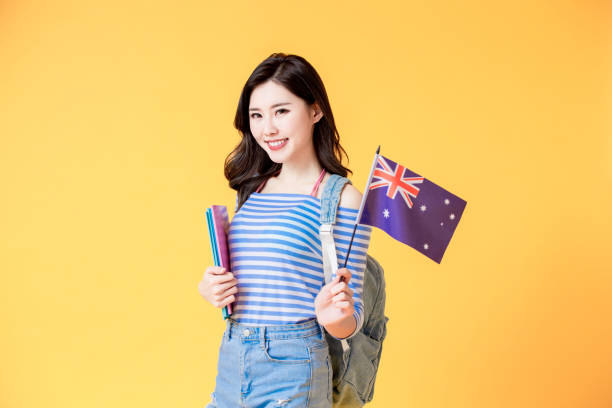 asian student smile to you asian female student smile and look to you with Australian flag isolated yellow background university students australia stock pictures, royalty-free photos & images