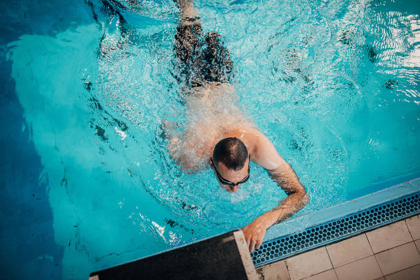 istock Young man with disability training in swimming pool indoors 1249757538