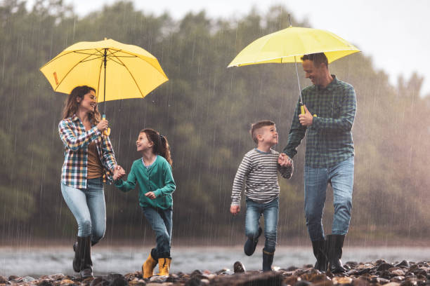 istock Happy family having fun while running on a rainy day at riverbank. 1249758643
