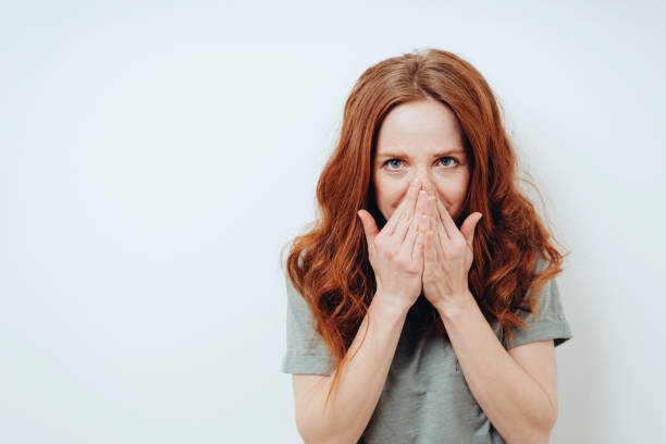 istock Embarrassed young woman hiding behind her hands 1249758719
