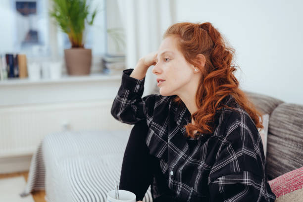 istock Dejected young woman sitting thinking 1249758836