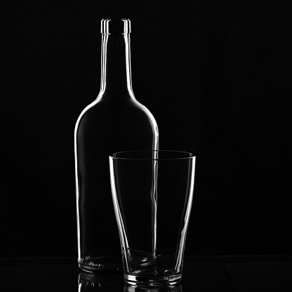 the contour of the bottle is outlined by light. glass photo on black background