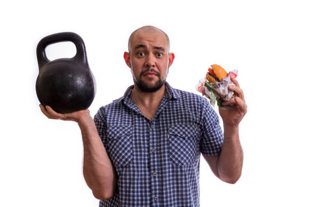 istock A bearded, fat man with a Burger and a weight in his hands. 1249761085