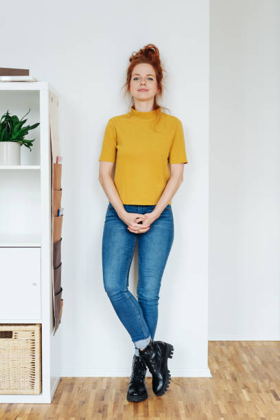 Relaxed young woman leaning against a white wall