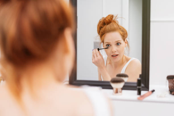 istock Pretty young woman applying mascara 1249763490