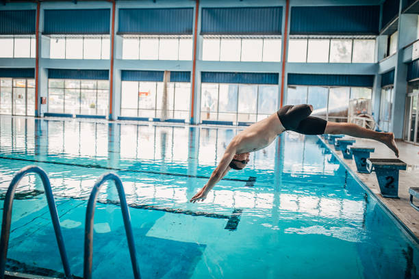 istock Man with disability jumping in swimming pool indoors 1249764699