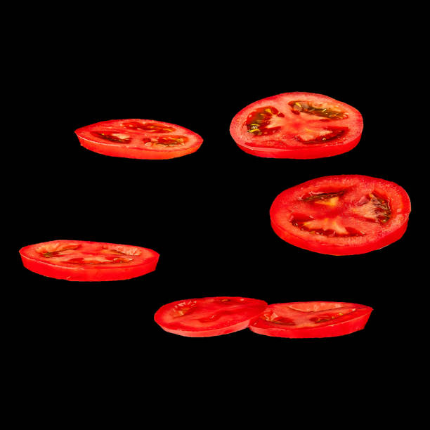 Flying tomato. Sliced red tomato isolated on black background. Levity vegetable floating in the air.