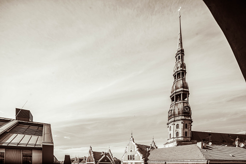 Sunny day in old town of Riga, Latvia. View of red tile roofs and St. Peter's Church spire. Observation tower. Sepia.