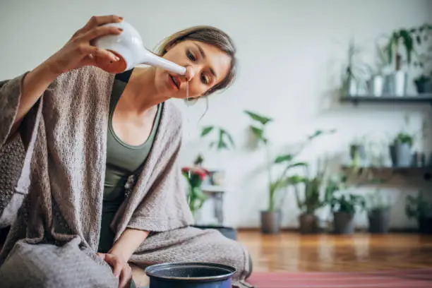 One beautiful young woman using neti pot at home after yoga practice.