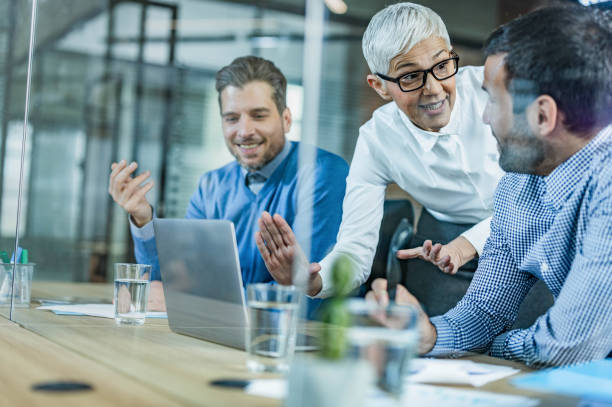 istock Happy business team talking while working on laptop in the office. 1249768099