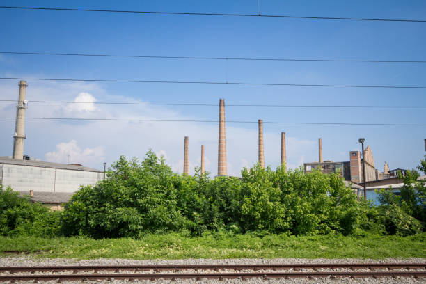 istock Panorama of an abandoned industrial factory complex with its typical tall red brick chimneys while cables and railway tracks are visible in front, in Pancevo, Serbia. 1249769185