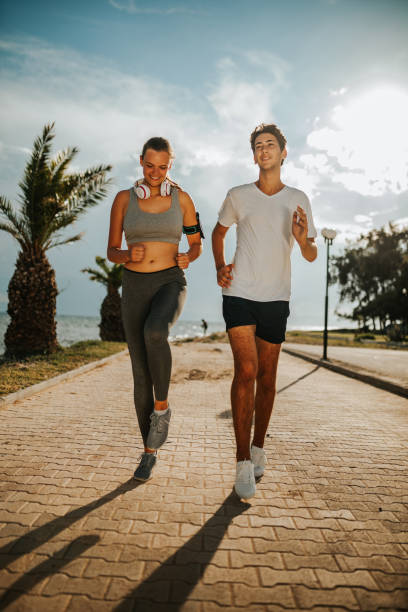 istock Young couple jogging by the sea 1249769651