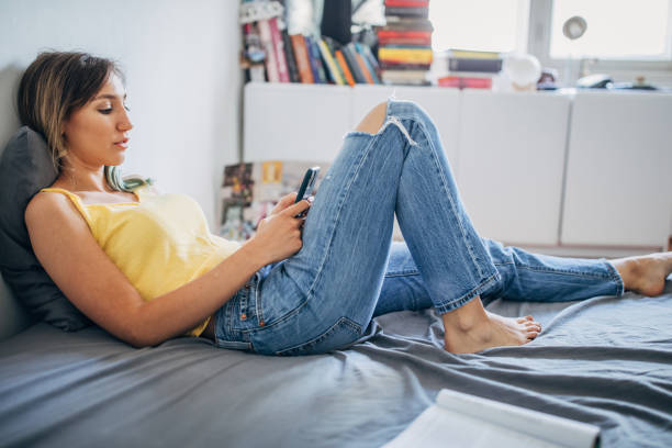 istock Beautiful woman lying on her bed and using smart phone 1249773717