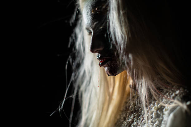 istock Female vampire with bloody lips after biting victim 1249775624