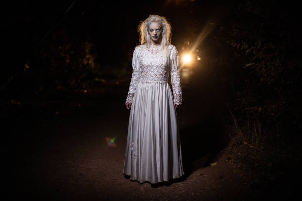 istock Witch in wedding dress standing on a road at night 1249775818