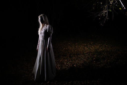 Young woman in scary witch costume for Halloween at forest during night