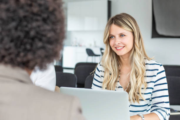 istock Young businesswoman using a laptop while she talks to employee in office 1249776135