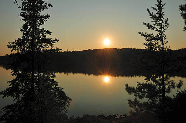 sunset on Saganagons Reflections of the sun on Saganagons Lake in the Quetico boundary waters canoe area stock pictures, royalty-free photos & images