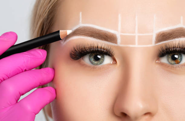 frau mit permanenten make-up tattoo auf ihren augenbrauen. nahaufnahme kosmetikerin tun tätowierung augenbraue. grüne augen schließen sich. professionelle make-up und kosmetik hautpflege. - removing tweezing eyebrows eyebrow caucasian stock-fotos und bilder