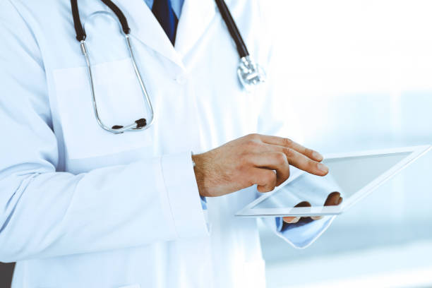 istock Doctor man using tablet computer for network research or virtual disease treatment, hands close-up. Perfect medical service in clinic. Modern medicine, medic data and healthcare concepts. Toned picture 1249779269