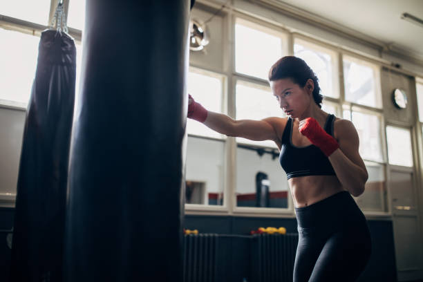 istock One woman kickboxer punching a punching bag 1249779416