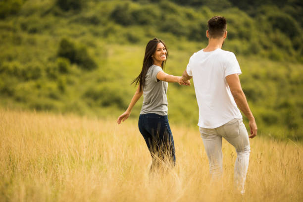 istock Happy young couple in love walking through grass field 1249781576