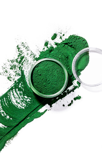 Organic green spirulina chlorella algae powder splash on white background. Creative concept of cosmetics and superfood
