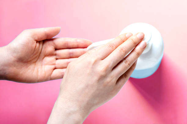 istock A woman sprays her hands with antiseptic from a plastic spray bottle. Hands with a bottle close-up on a pink background. 1249783547