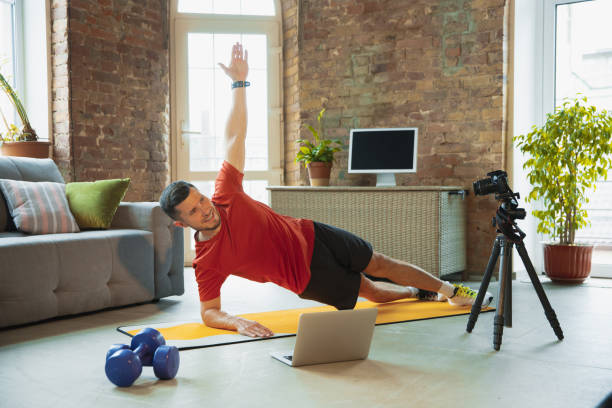 istock Young caucasian man training at home during quarantine of coronavirus outbreak, doing exercises of fitness, aerobic. Staying sportive during insulation. 1249790579