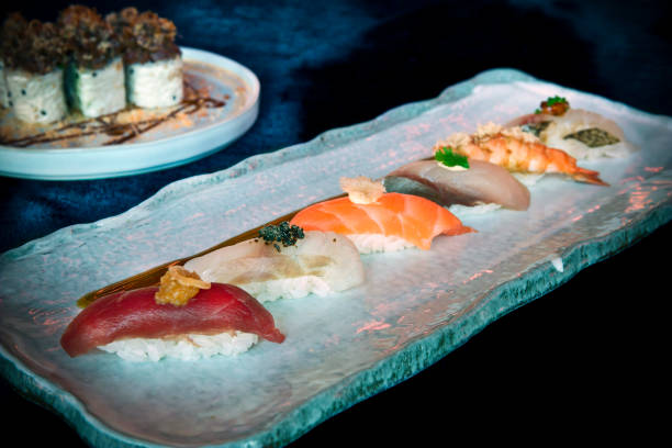 Sushi Platter Low side angle close-up shot of the sushi platter with Salmon, Sea Bass, Yellowtail, Red Snapper, Akami Tuna and Fatty Belly Tuna sushi on a white plate salmon and red snapper stock pictures, royalty-free photos & images