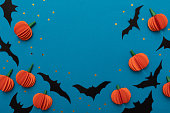 Halloween blue background with black bats and orange pumpkins. Modern design. Holiday party decoration. Flat lay.