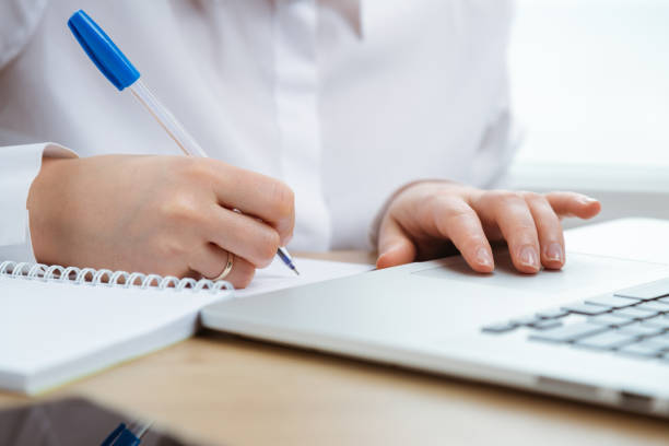istock A close up of woman's hands, working on a notebook and writing. 1249791193